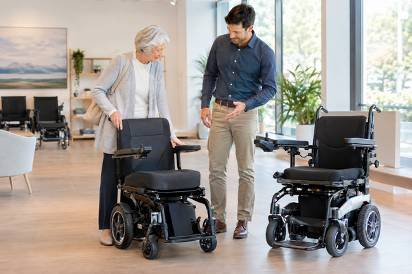 Older adult and family member comparing electric wheelchair options in a bright mobility showroom