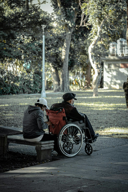 Senior couple outdoors by a lake on a damp autumn morning, one in a wheelchair — knowing whether an electric wheelchair can get wet keeps outings worry-free