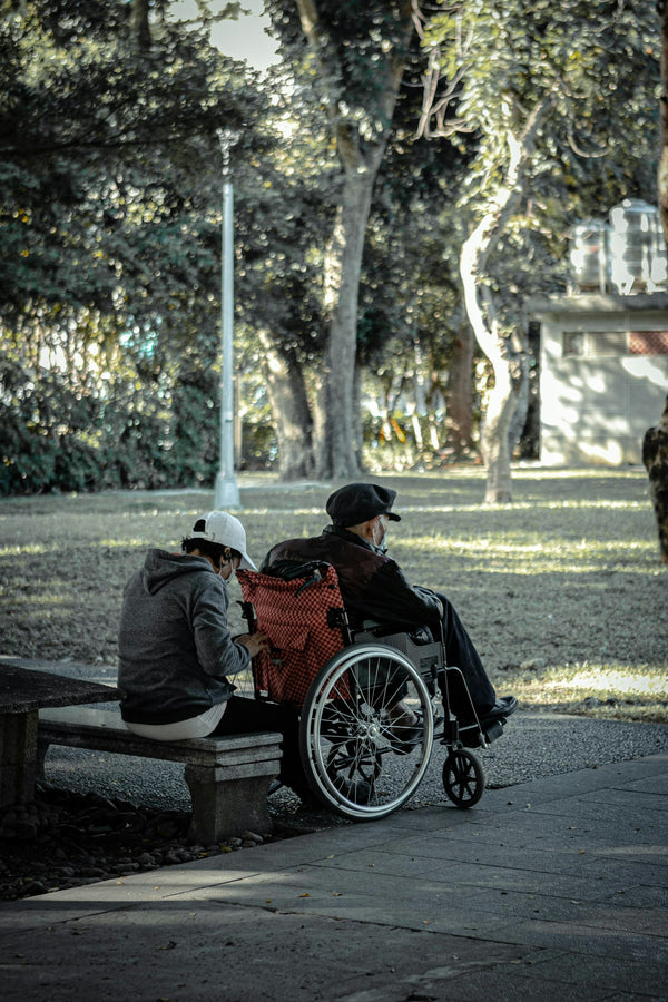 Senior couple outdoors by a lake on a damp autumn morning, one in a wheelchair — knowing whether an electric wheelchair can get wet keeps outings worry-free