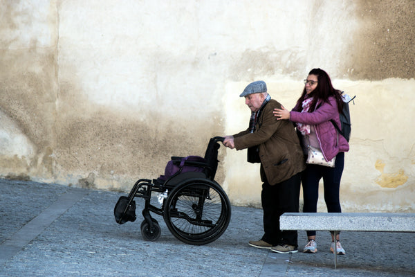 A caregiver helping an older man get comfortable in his wheelchair, illustrating how to use an electric wheelchair for the first time