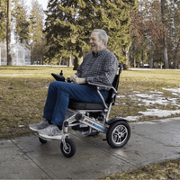 Senior riding a lightweight electric wheelchair outdoors